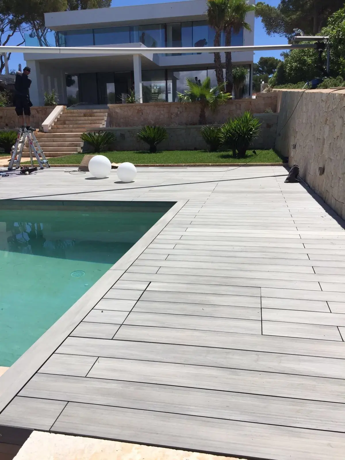 Pasillo de tarima de madera tecnológica junto a una piscina