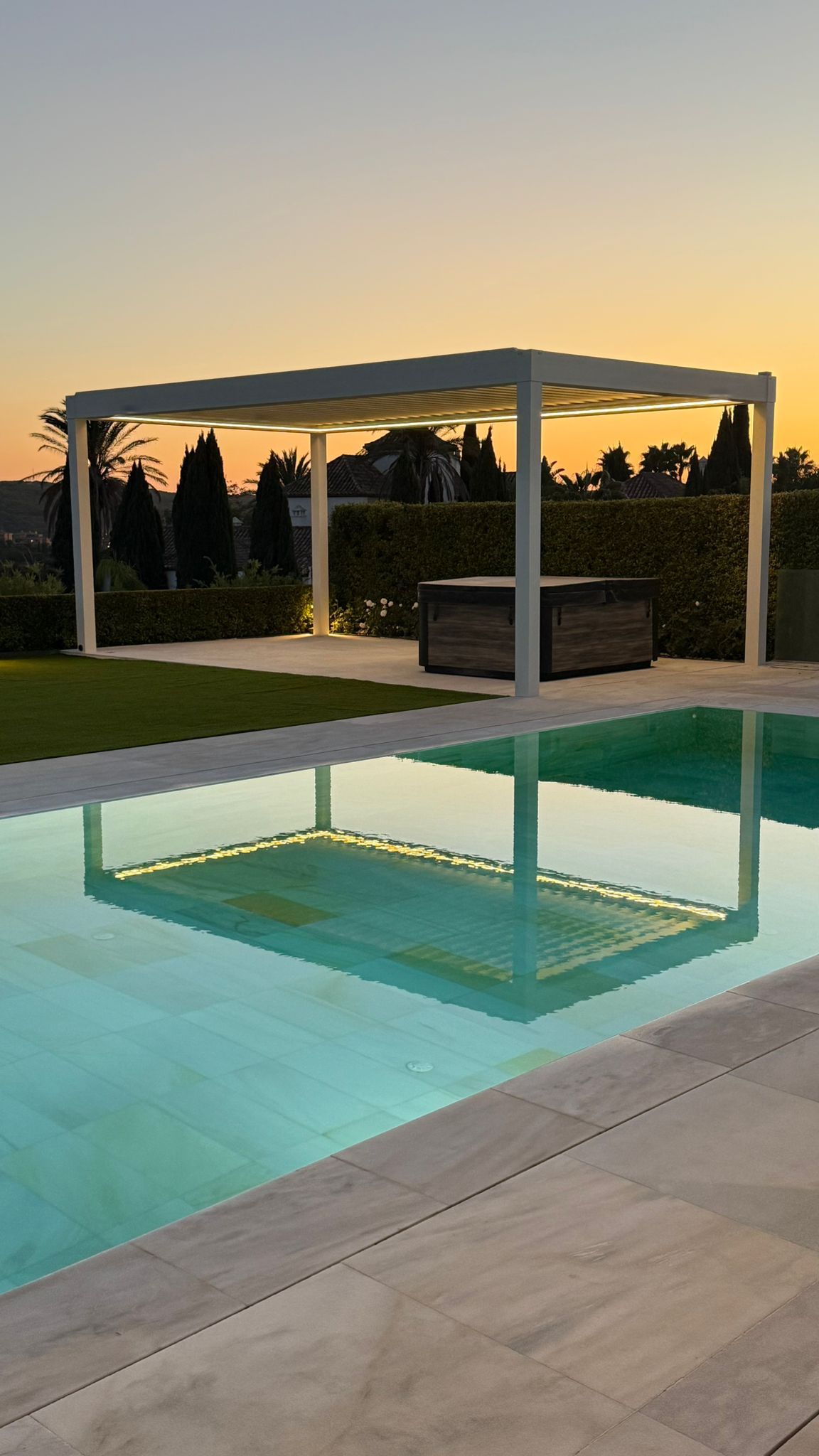 Pérgola bioclimática autoportante junto a piscina al atardecer
