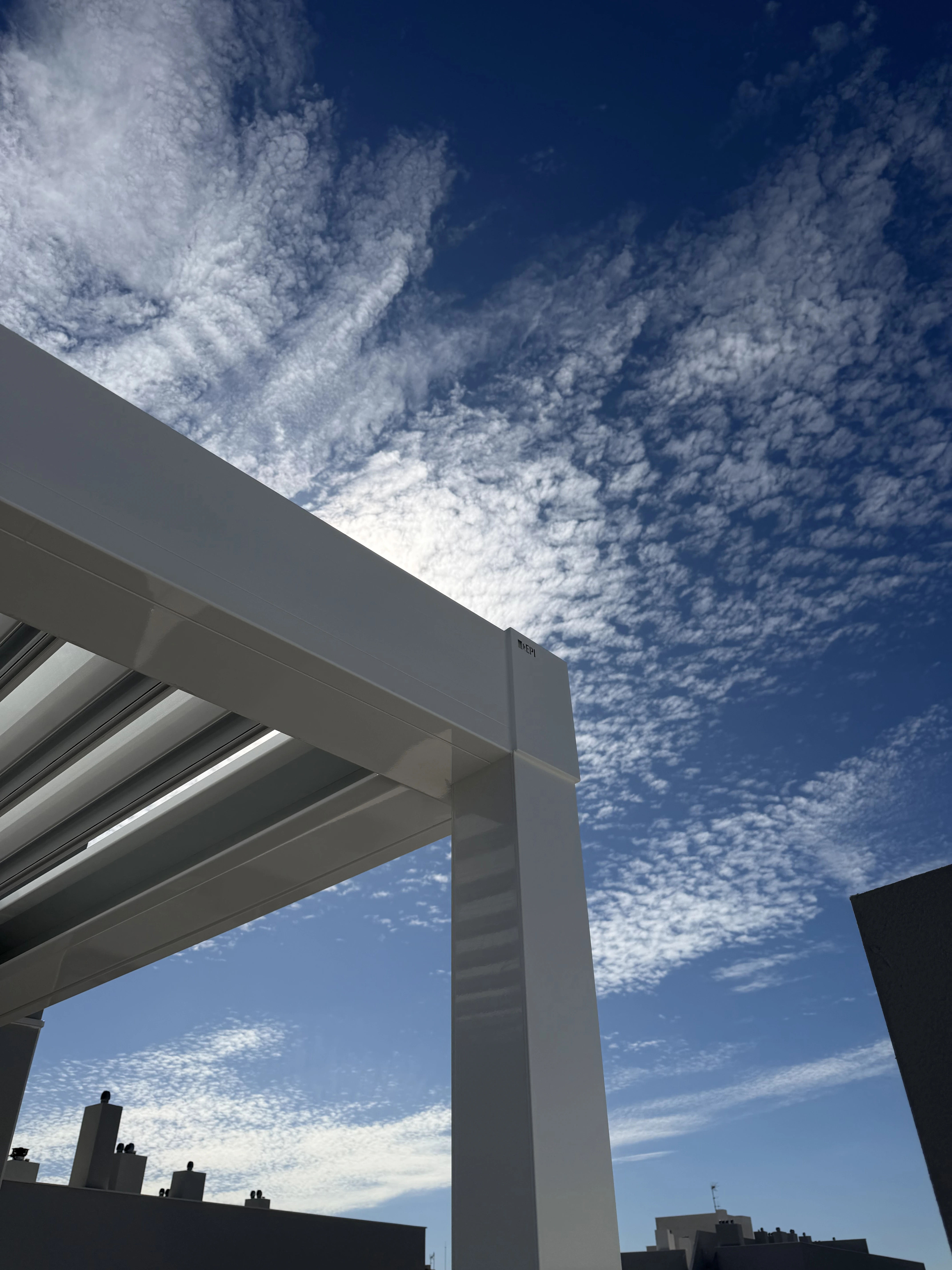 Pérgola bioclimática contrapicada con cielo despejado en villa de zona costera de Cádiz