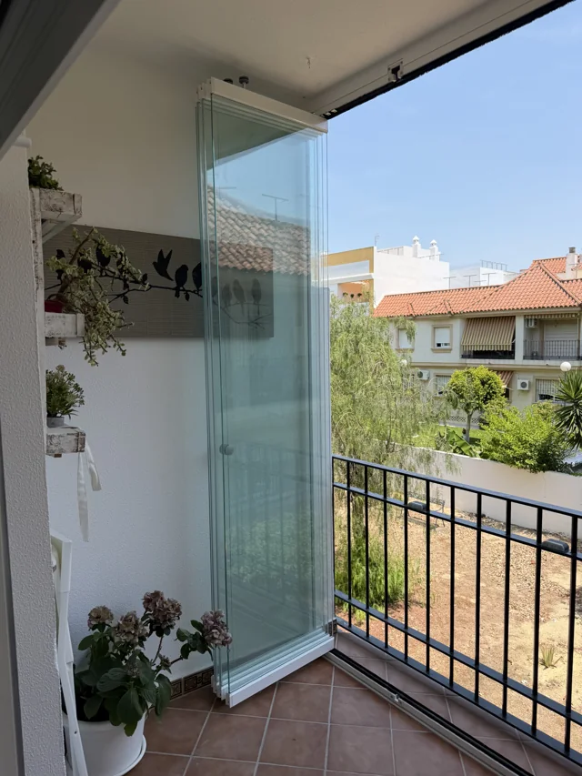 Detalle de las hojas de cristal plegadas en el lateral del balcón