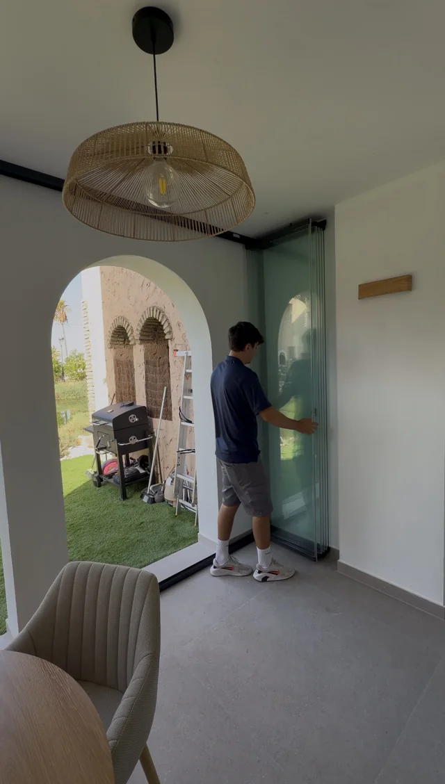 Cortina de cristal gris instalada por detrás del arco de un porche