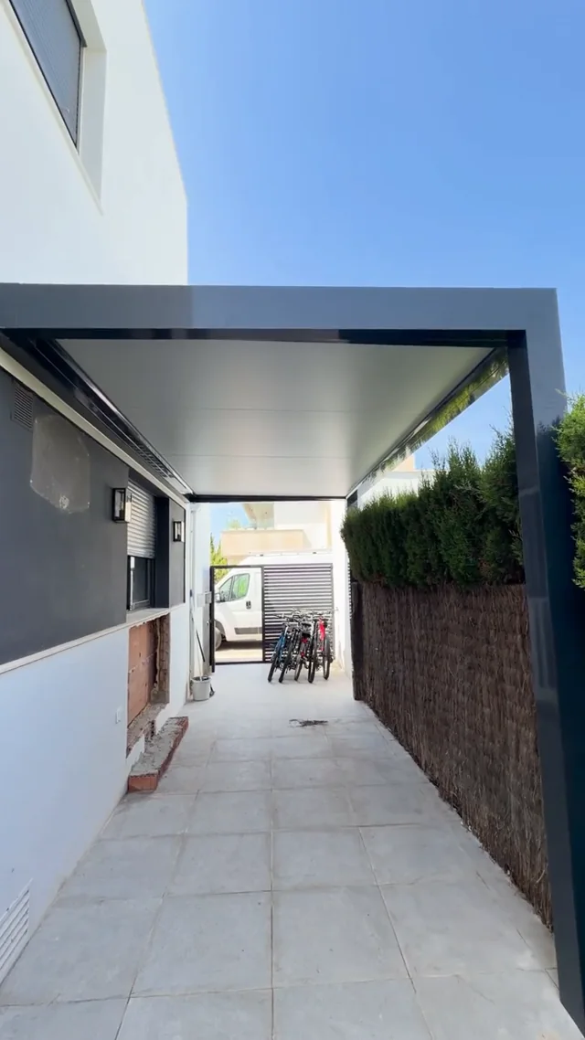 Pérgola gris de panel sándwich junto a una vivienda en Puerto Sherry
