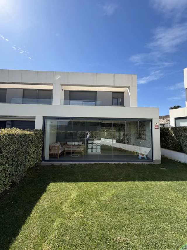 Vista de la vivienda y el jardín con la cortina de cristal cerrada
